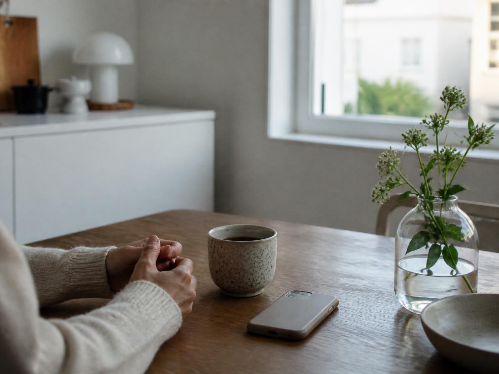 Rolig morgen ved et køkkenbord med kaffe og en telefon